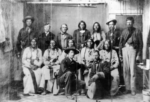 Standing L-R: Unidentified, Dexter Colley (son of Agent Samuel Colley), John S. Smith, Heap of Buffalo, Bosse, Sheriff Amos Steck, Unidentified soldier. Seated L-R: White Antelope, Bull Bear, Black Kettle, Neva, Na-ta-Nee (Knock Knee). Kneeling L-R: Major Edward W. Wynkoop, Captain Silas Soule.
