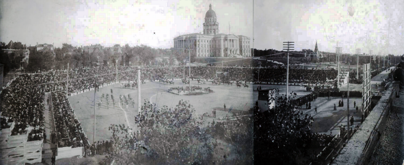 People crowd bleachers in an arena, probably for the Festival of Mountain and Plain, at the corner of Colfax and Broadway Streets, in Denver, Colorado; a marching band and horses are in the arena. The Colorado State Capitol building is in the distance. [between 1890 and 1910?] Courtesy DPL Western History Collection Z-6110
